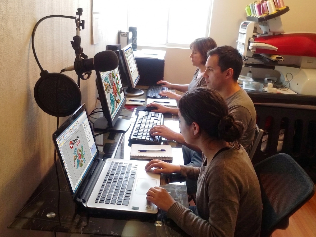 Alumnos trabajando diseños de bordado en computadora